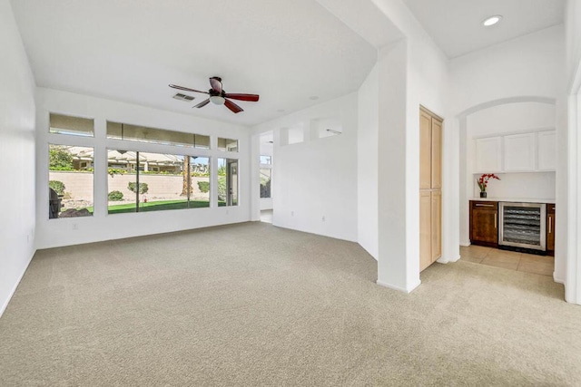 interior space featuring light carpet, wine cooler, and ceiling fan