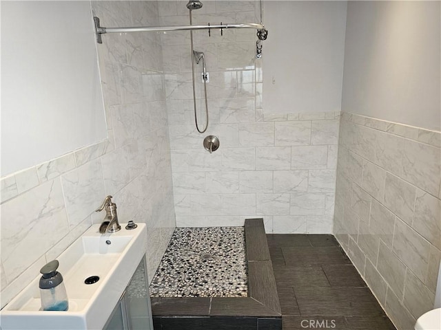 bathroom featuring a tile shower, tile walls, and sink