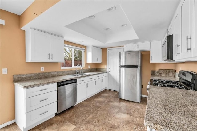 kitchen with sink, white cabinetry, light stone counters, appliances with stainless steel finishes, and a tray ceiling