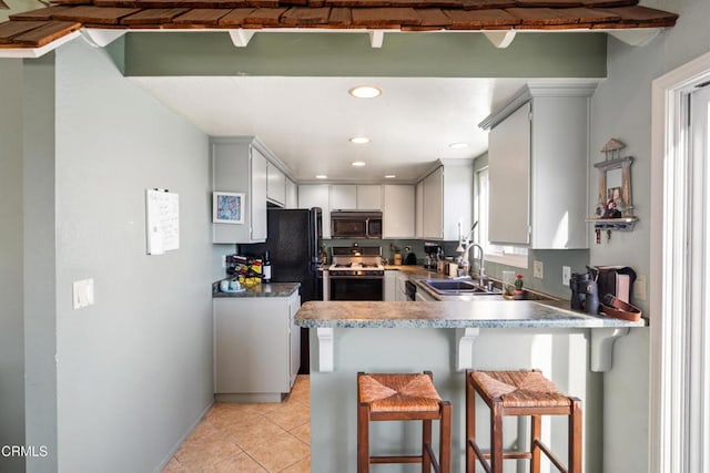 kitchen with white cabinetry, sink, kitchen peninsula, a breakfast bar, and black appliances