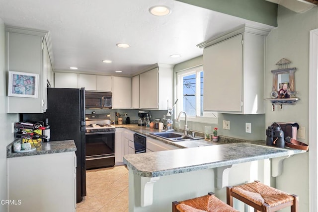 kitchen featuring black appliances, sink, light tile patterned flooring, a kitchen bar, and kitchen peninsula