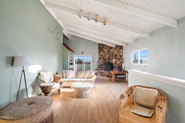 living room featuring a wealth of natural light, a fireplace, lofted ceiling with beams, and hardwood / wood-style flooring