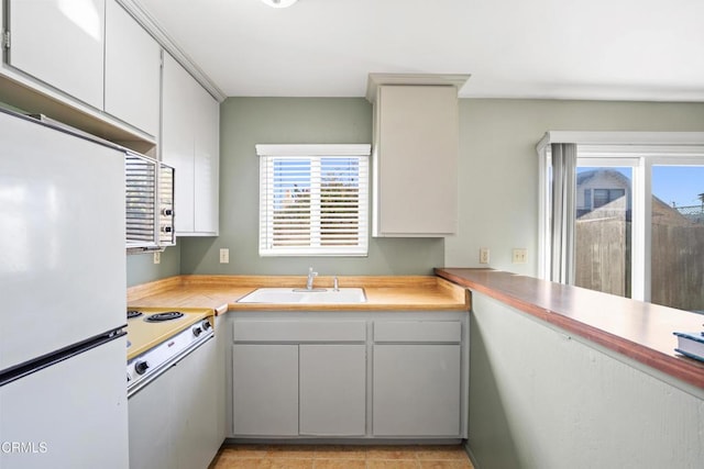 kitchen with white cabinets, white appliances, plenty of natural light, and sink