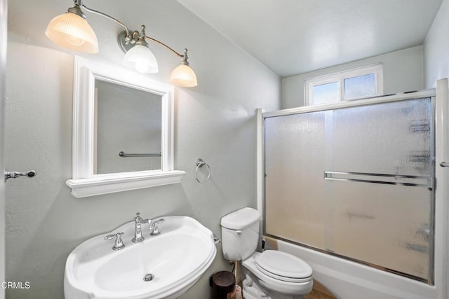 full bathroom with bath / shower combo with glass door, toilet, and sink