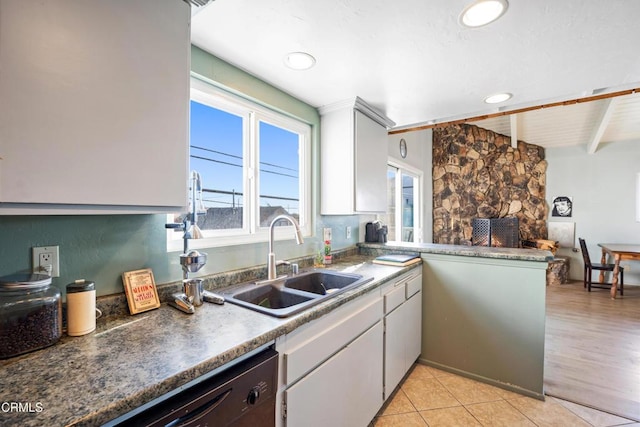 kitchen featuring dishwasher, sink, beamed ceiling, kitchen peninsula, and light hardwood / wood-style floors