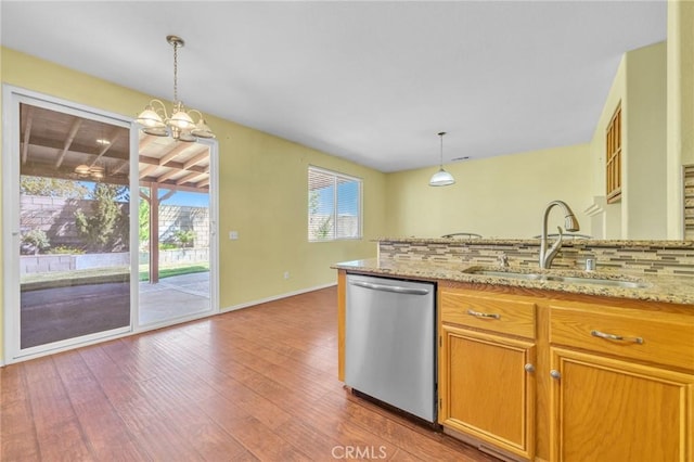 kitchen with light stone countertops, sink, an inviting chandelier, stainless steel dishwasher, and pendant lighting