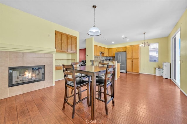 dining room with hardwood / wood-style flooring, a tile fireplace, and a chandelier