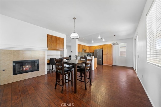 dining room featuring a tiled fireplace, baseboards, dark wood-type flooring, and recessed lighting