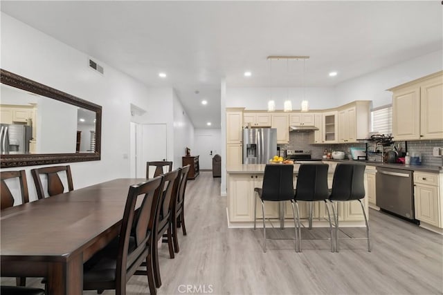 kitchen featuring a center island, hanging light fixtures, stainless steel appliances, light hardwood / wood-style flooring, and cream cabinets