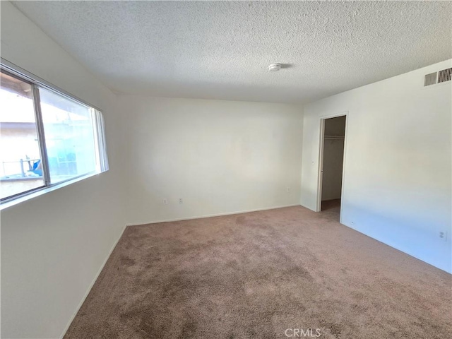 carpeted spare room featuring a textured ceiling