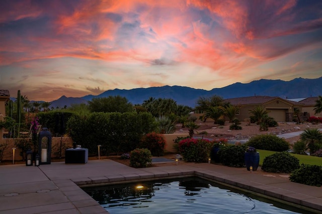 pool at dusk featuring a patio area and a mountain view