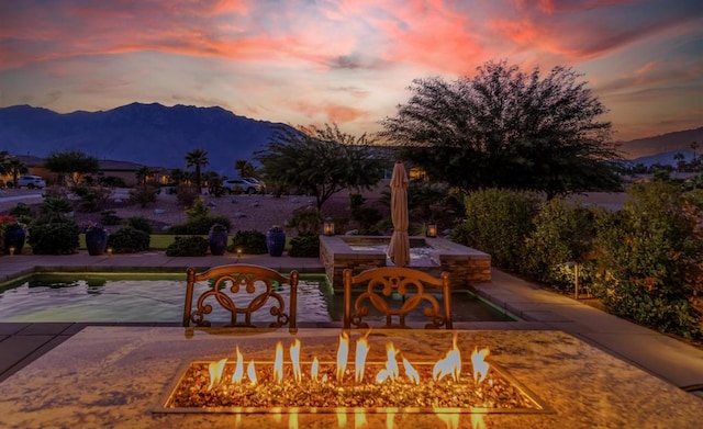 patio terrace at dusk with a mountain view and a fire pit