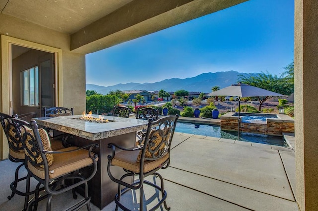 view of patio featuring a fire pit, a mountain view, a swimming pool with hot tub, and exterior bar