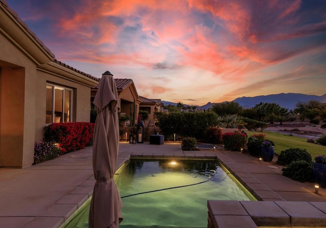 pool at dusk with a mountain view and a patio area