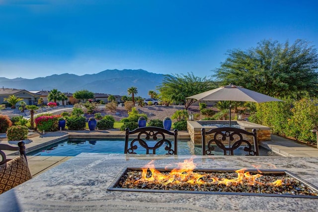 view of swimming pool with a patio area, a mountain view, and an outdoor fire pit