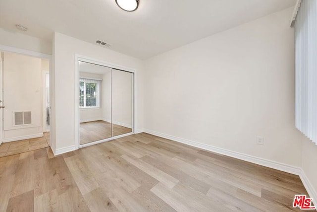 unfurnished bedroom featuring light hardwood / wood-style floors and a closet