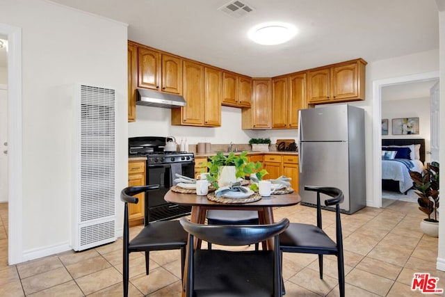 kitchen featuring black range with gas stovetop, stainless steel fridge, and light tile patterned floors