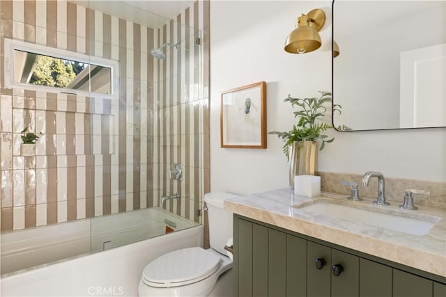 full bathroom featuring vanity, tiled shower / bath combo, and toilet