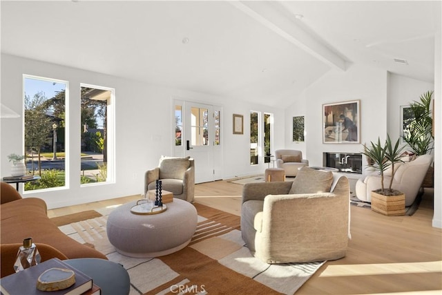 living room with light wood-type flooring, lofted ceiling with beams, and a healthy amount of sunlight