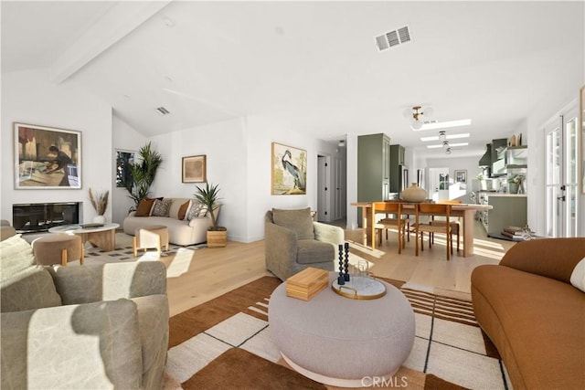 living room featuring lofted ceiling with beams, light hardwood / wood-style floors, and ceiling fan