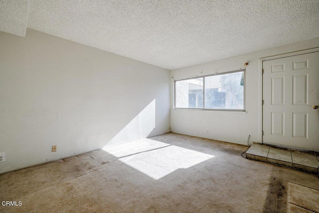 unfurnished room with light carpet and a textured ceiling