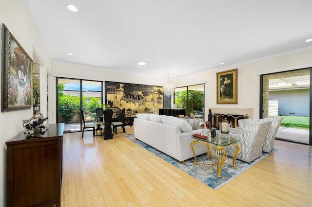 living room with light hardwood / wood-style flooring, ornamental molding, and a notable chandelier