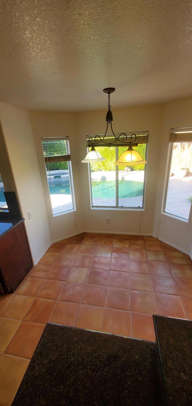 unfurnished dining area with tile patterned flooring and a textured ceiling