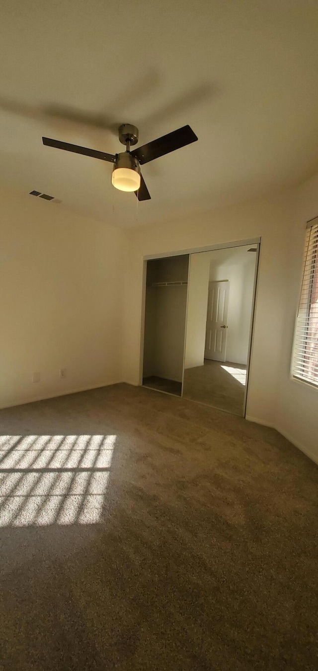 empty room featuring ceiling fan and carpet