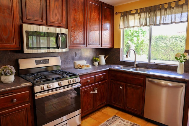 kitchen with sink, decorative backsplash, light tile patterned flooring, and appliances with stainless steel finishes