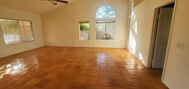 tiled spare room with ceiling fan and high vaulted ceiling