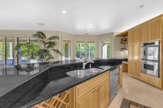 kitchen with sink, stainless steel appliances, dark stone counters, and light tile patterned flooring