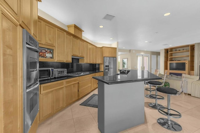 kitchen with appliances with stainless steel finishes, an island with sink, sink, a breakfast bar, and light tile patterned floors