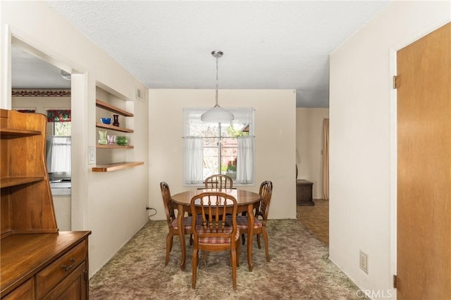 dining space with light carpet, a textured ceiling, and built in shelves