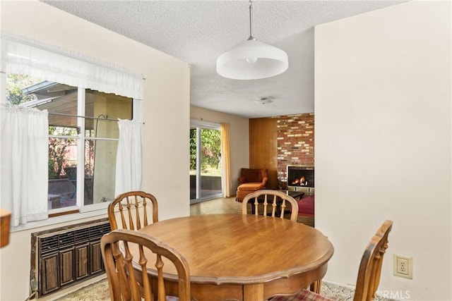 dining space featuring a brick fireplace and a textured ceiling