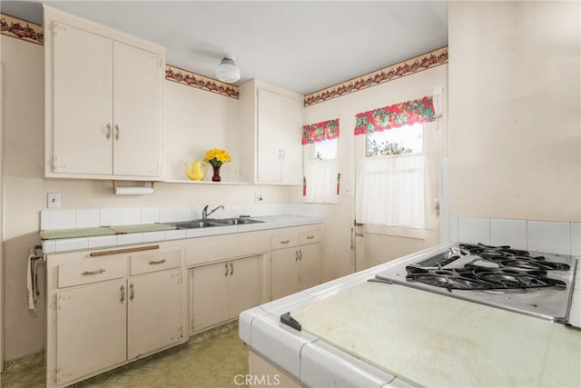 kitchen featuring tile counters, cream cabinetry, gas cooktop, and sink