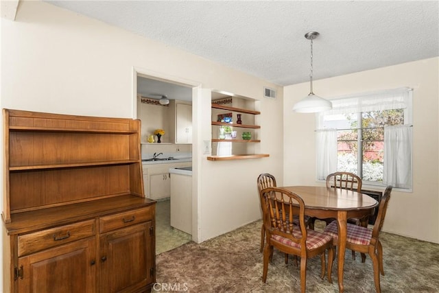 carpeted dining space featuring sink and a textured ceiling