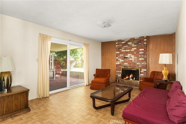 living room featuring light parquet floors, wood walls, and a fireplace