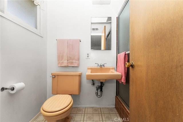 bathroom with toilet and a shower with door