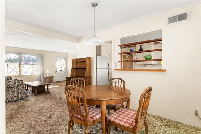 carpeted dining area with a textured ceiling