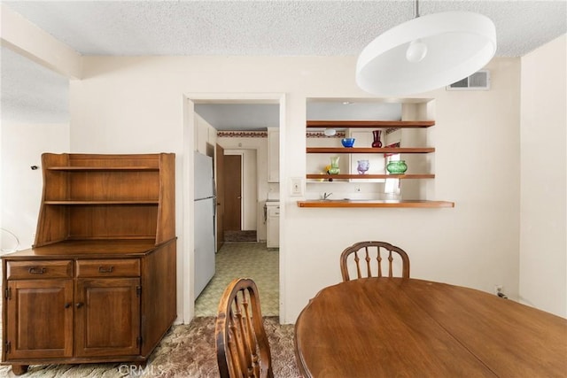 unfurnished dining area featuring a textured ceiling