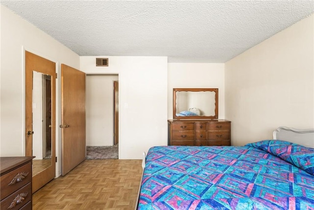 bedroom featuring light parquet flooring and a textured ceiling