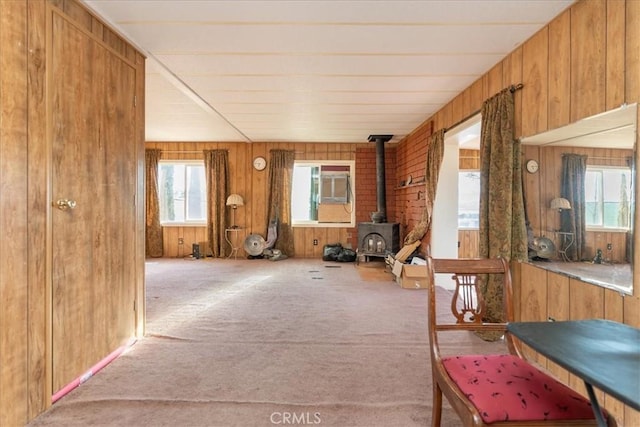 interior space featuring a wood stove, light carpet, and wooden walls