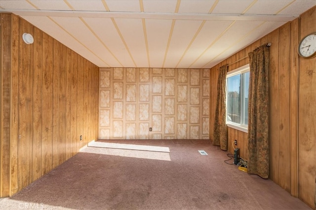 carpeted empty room featuring wooden walls