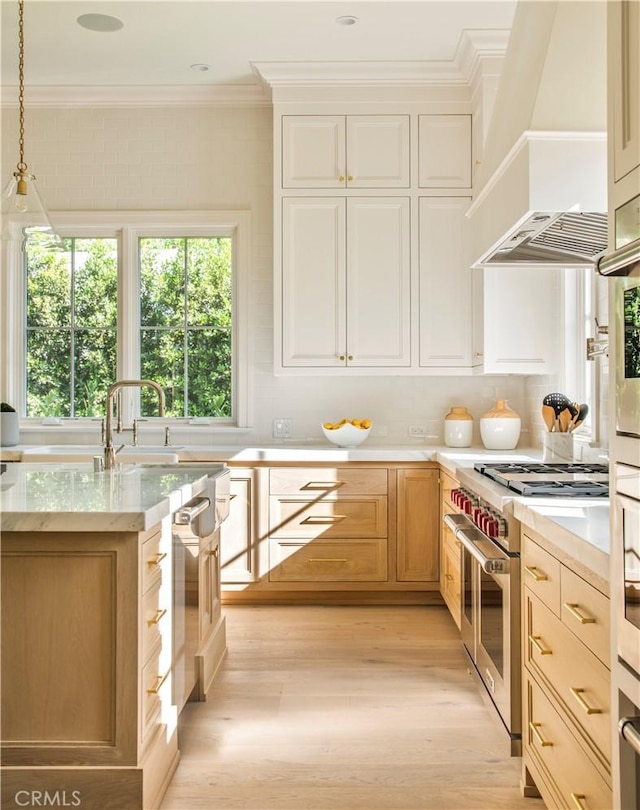 kitchen with pendant lighting, custom exhaust hood, high end stainless steel range, light wood-type flooring, and ornamental molding