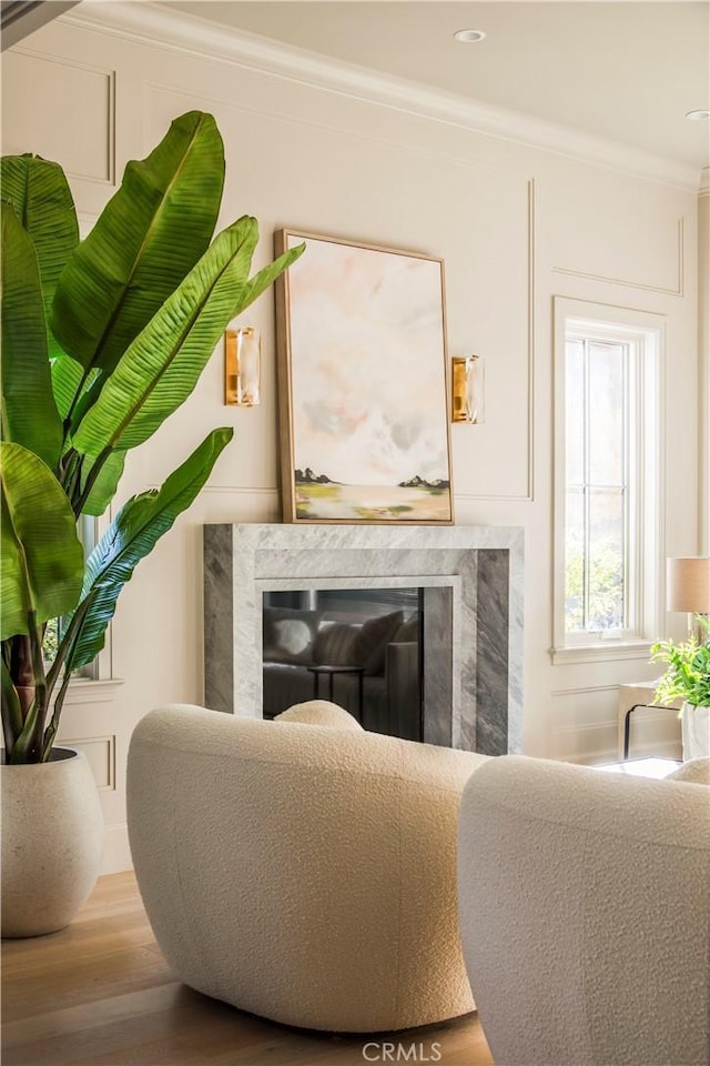 interior space with wood-type flooring, crown molding, and a high end fireplace