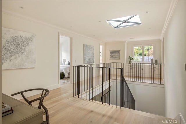 corridor featuring a skylight, light hardwood / wood-style floors, and ornamental molding