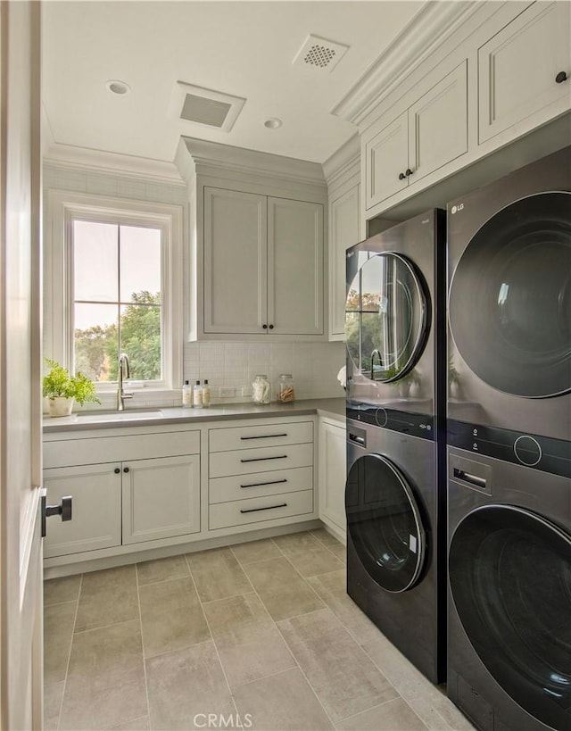 laundry room with sink, cabinets, crown molding, light tile patterned floors, and stacked washer and clothes dryer