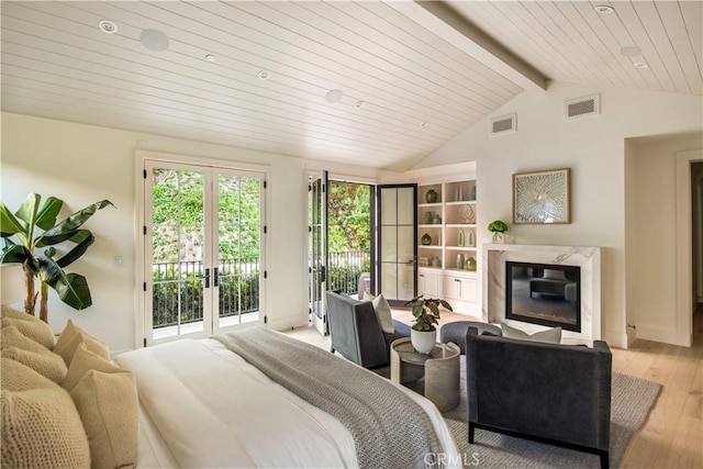 bedroom featuring access to outside, french doors, vaulted ceiling with beams, a fireplace, and light hardwood / wood-style floors