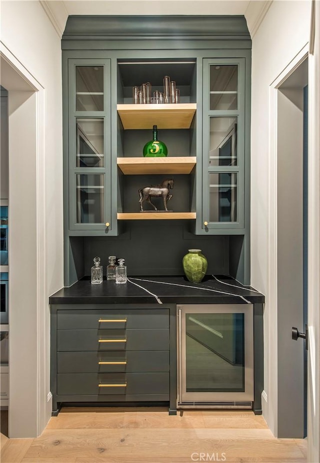 bar with oven, crown molding, and light hardwood / wood-style flooring