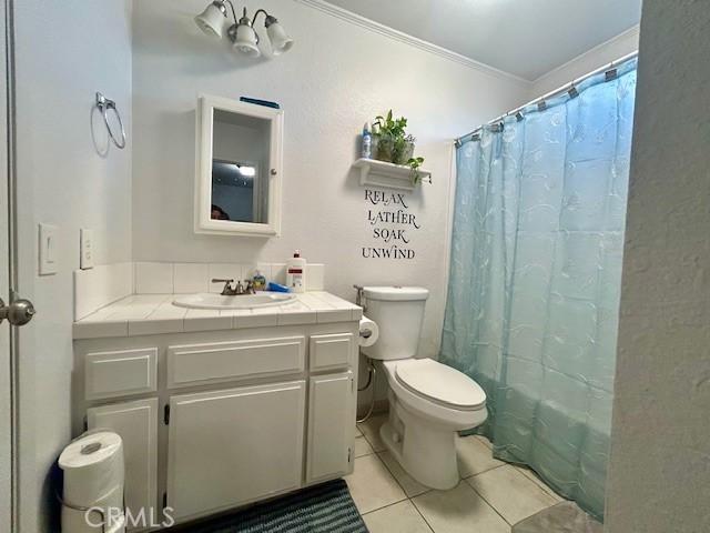 full bathroom featuring shower / bath combo, tile patterned flooring, crown molding, toilet, and vanity